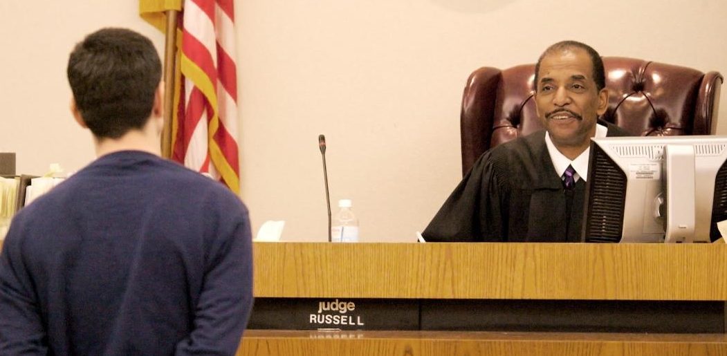A male speaks to the judge in a courtroom.